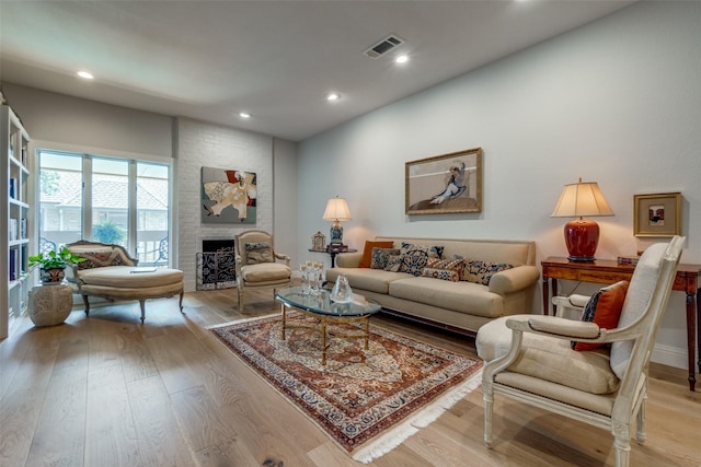 living room featuring light hardwood / wood-style floors and a brick fireplace