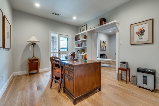 office area featuring a large fireplace and light wood-type flooring