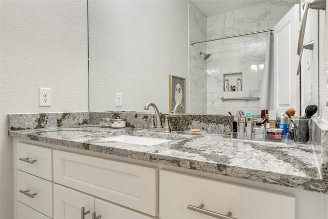 bathroom with a tile shower and vanity