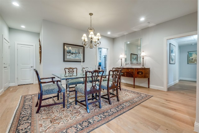 dining space with light hardwood / wood-style floors and a notable chandelier