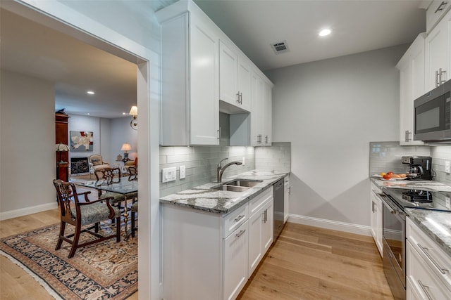 kitchen with tasteful backsplash, white cabinetry, sink, and appliances with stainless steel finishes