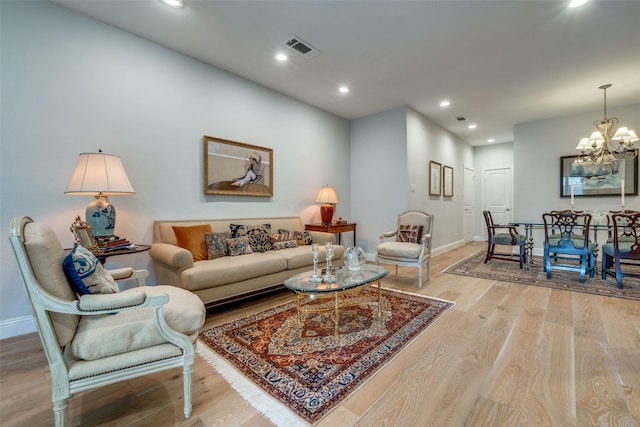 living room featuring light wood-type flooring and a notable chandelier