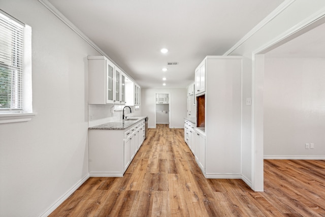 kitchen with light stone counters, sink, light hardwood / wood-style floors, and white cabinets