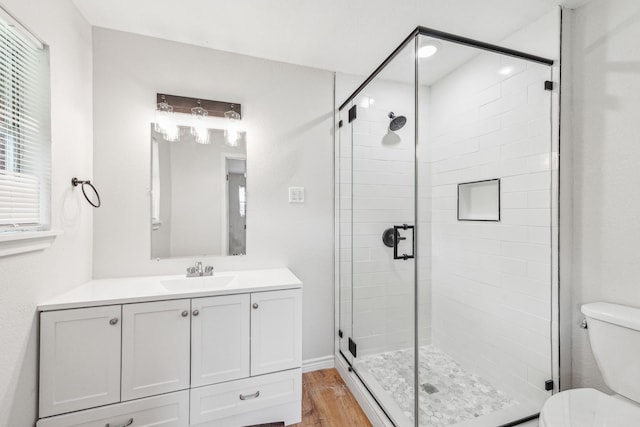 bathroom with a shower with shower door, toilet, wood-type flooring, and oversized vanity