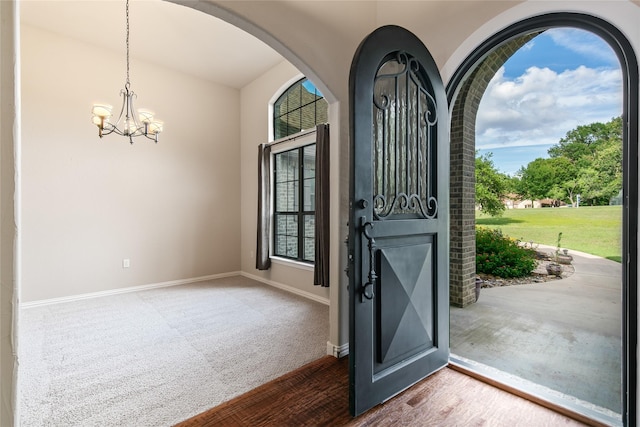 foyer entrance featuring a healthy amount of sunlight, an inviting chandelier, and carpet floors