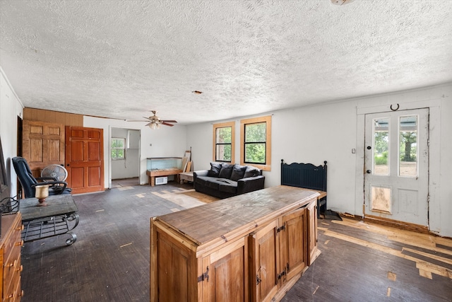 living room featuring dark hardwood / wood-style flooring, ceiling fan, and a textured ceiling