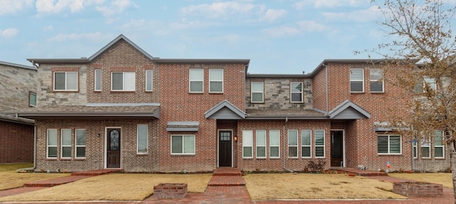 multi unit property featuring stone siding, brick siding, and a front yard