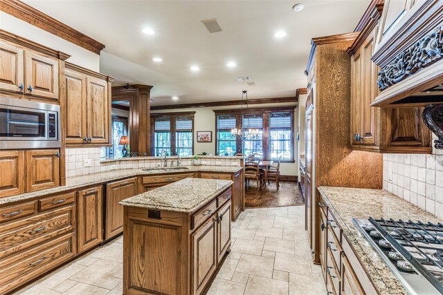 kitchen with decorative light fixtures, a center island, stainless steel appliances, sink, and light wood-type flooring