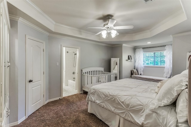 carpeted bedroom with crown molding, a raised ceiling, connected bathroom, and ceiling fan