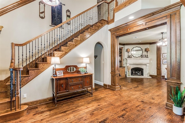 stairs with ceiling fan, ornamental molding, wood-type flooring, and a high ceiling