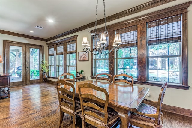 dining space featuring french doors, ornamental molding, wood-type flooring, and a chandelier