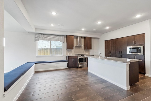 kitchen featuring a center island, dark brown cabinetry, stainless steel appliances, and wall chimney exhaust hood