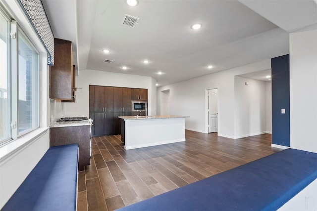 kitchen with dark brown cabinetry, a center island, and built in microwave