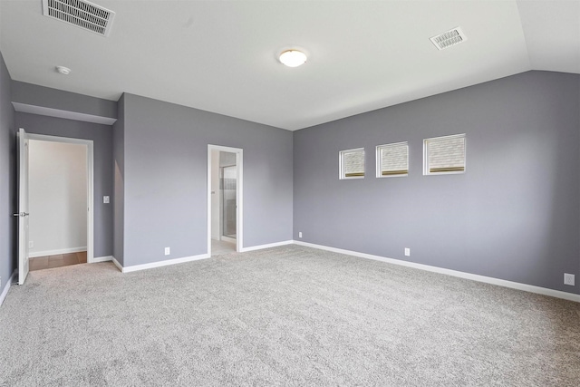 unfurnished bedroom featuring a spacious closet, light colored carpet, and lofted ceiling