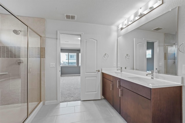 bathroom featuring tile patterned floors, vanity, a textured ceiling, and walk in shower