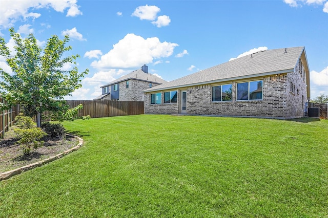 rear view of house with a yard and central AC unit