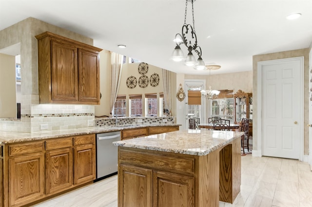 kitchen with backsplash, decorative light fixtures, stainless steel dishwasher, light stone countertops, and a notable chandelier