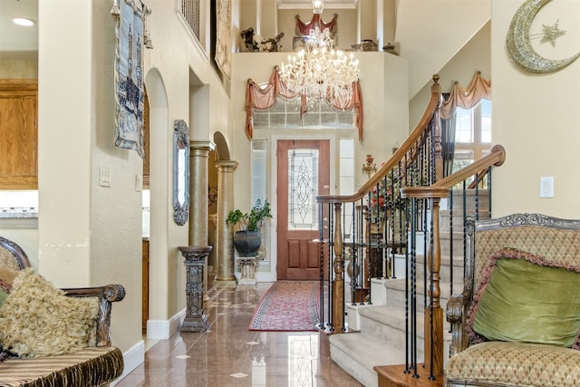 entryway featuring a notable chandelier, a towering ceiling, and a wealth of natural light