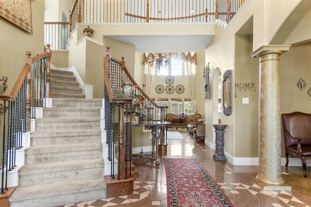 entrance foyer featuring ornate columns, a towering ceiling, and a chandelier