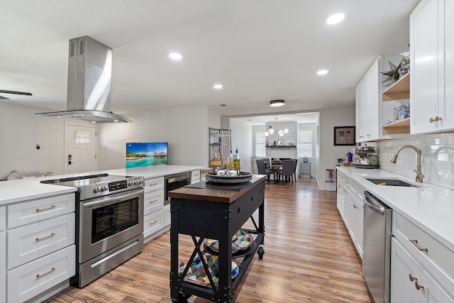 kitchen with white cabinetry, stainless steel appliances, exhaust hood, light hardwood / wood-style flooring, and sink