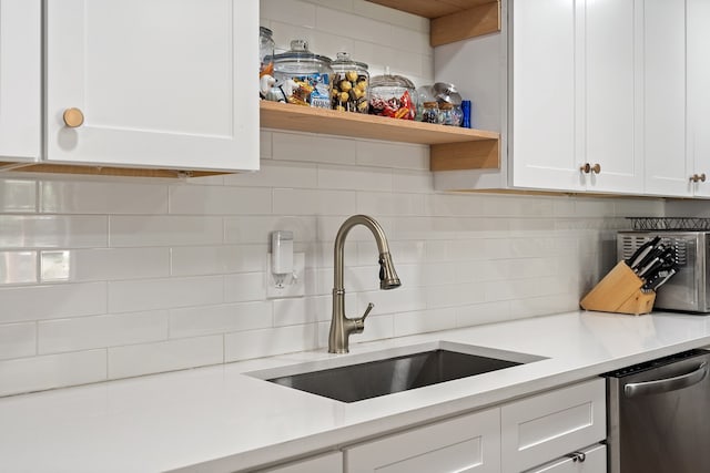 kitchen featuring decorative backsplash, stainless steel dishwasher, sink, and white cabinets