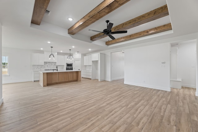 unfurnished living room featuring ceiling fan, beam ceiling, and light hardwood / wood-style floors