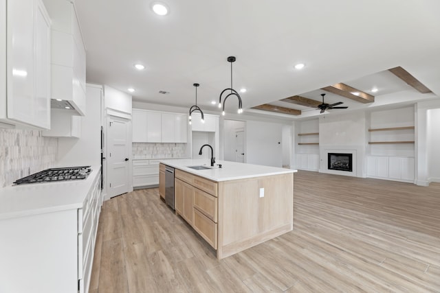 kitchen with sink, hanging light fixtures, a kitchen island with sink, stainless steel appliances, and white cabinets