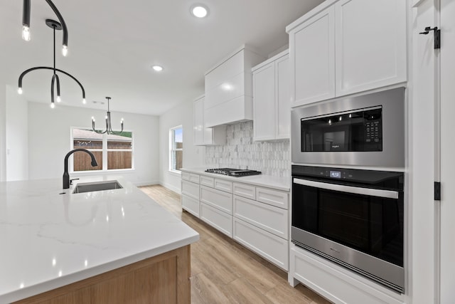 kitchen with appliances with stainless steel finishes, pendant lighting, and white cabinetry