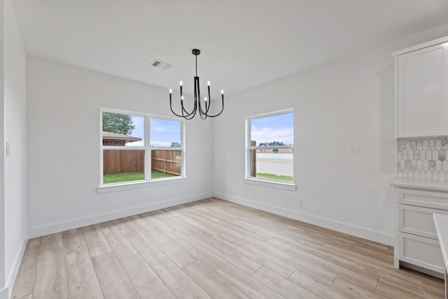 unfurnished dining area with an inviting chandelier and light hardwood / wood-style flooring