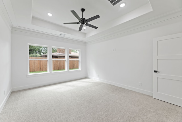 carpeted empty room with ceiling fan, a tray ceiling, and ornamental molding