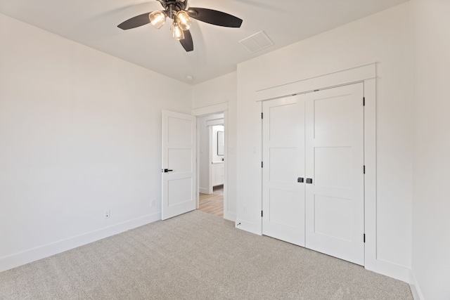 unfurnished bedroom featuring ceiling fan, a closet, and light carpet