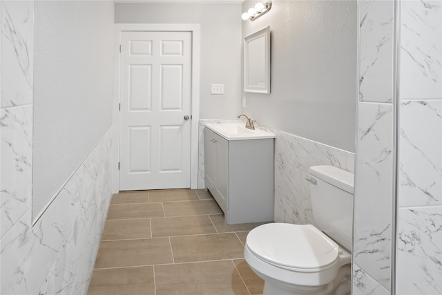 bathroom with tile floors, tile walls, toilet, and vanity