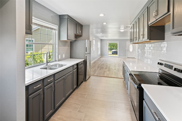 kitchen with sink, tasteful backsplash, light tile flooring, and stainless steel appliances