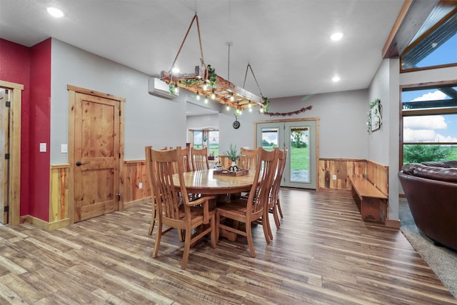 dining area with a wall unit AC, hardwood / wood-style floors, and french doors