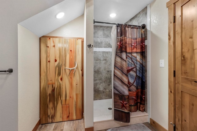 bathroom featuring wood-type flooring, a shower with shower curtain, and vaulted ceiling