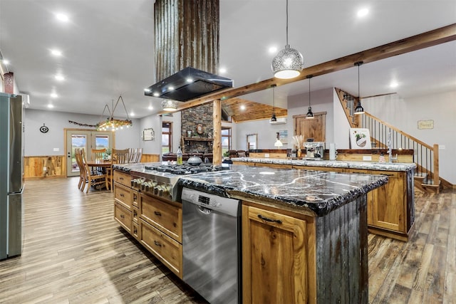 kitchen with kitchen peninsula, a kitchen island, hanging light fixtures, wood-type flooring, and appliances with stainless steel finishes