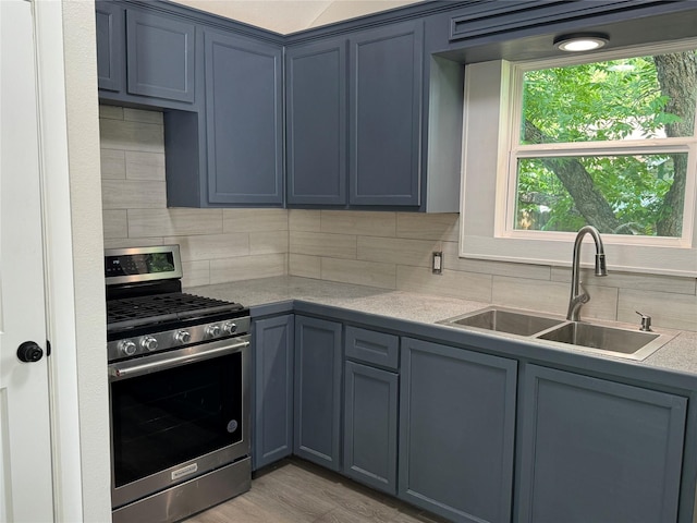 kitchen with stainless steel gas stove, decorative backsplash, sink, and light hardwood / wood-style flooring