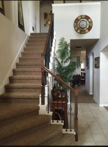953 Lake Forest Trl, Little Elm, TX 75068 - stairs featuring arched walkways, baseboards, tile patterned floors, and a high ceiling