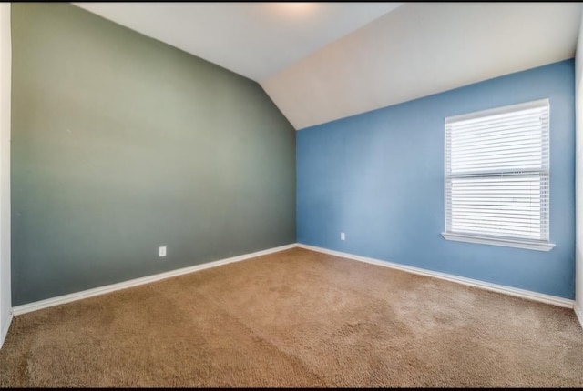 carpeted empty room with lofted ceiling