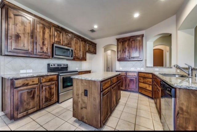 953 Lake Forest Trl, Little Elm, TX 75068 - kitchen with stainless steel appliances, arched walkways, backsplash, a sink, and light stone countertops