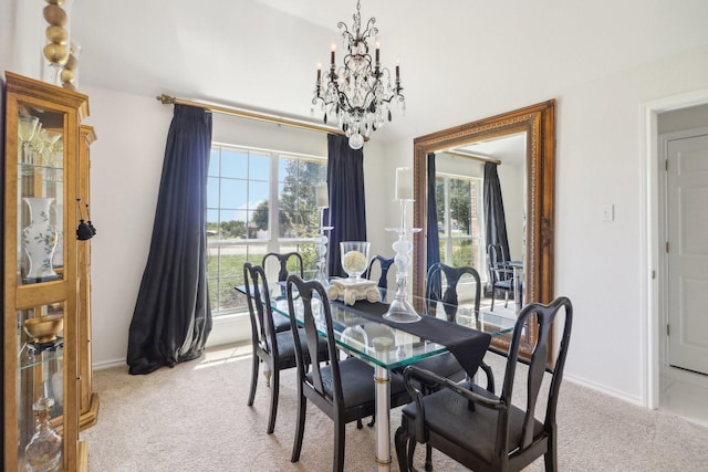 dining room featuring light colored carpet, a notable chandelier, and baseboards