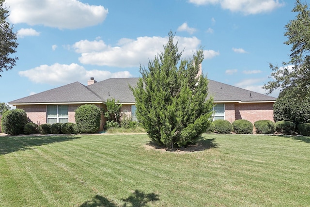 exterior space featuring a chimney, a lawn, and brick siding