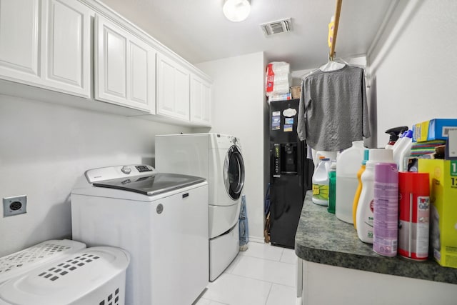 washroom featuring washer and clothes dryer, light tile patterned flooring, and cabinets