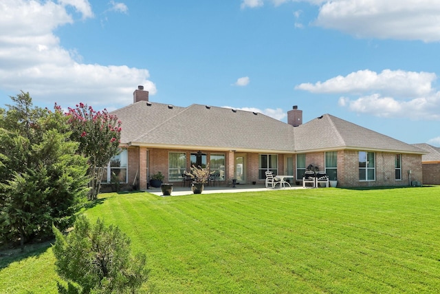 back of house with a patio area, a chimney, a lawn, and brick siding