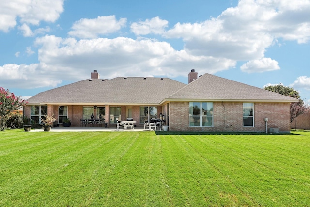 back of property with a patio area, brick siding, and a yard