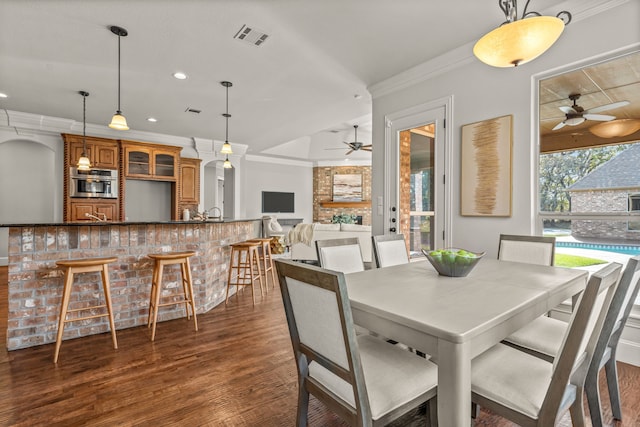 dining space featuring ceiling fan, dark wood-type flooring, and ornamental molding