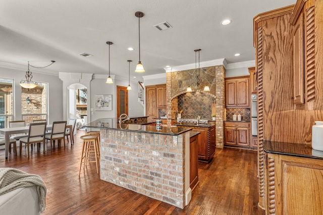 kitchen with decorative light fixtures, dark hardwood / wood-style flooring, and a kitchen island with sink