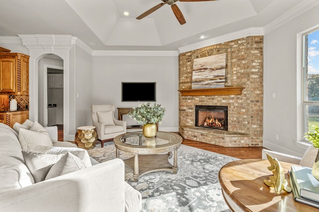 living room with a brick fireplace, wood-type flooring, and ornamental molding