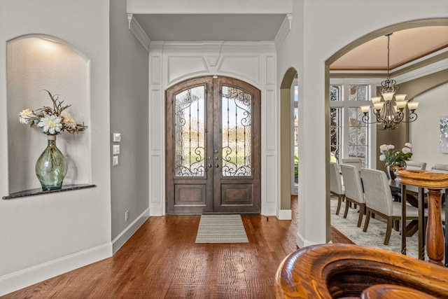 entryway featuring a chandelier, ornamental molding, dark wood-type flooring, and french doors