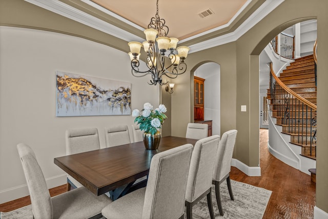 dining space with wood-type flooring, crown molding, and a chandelier